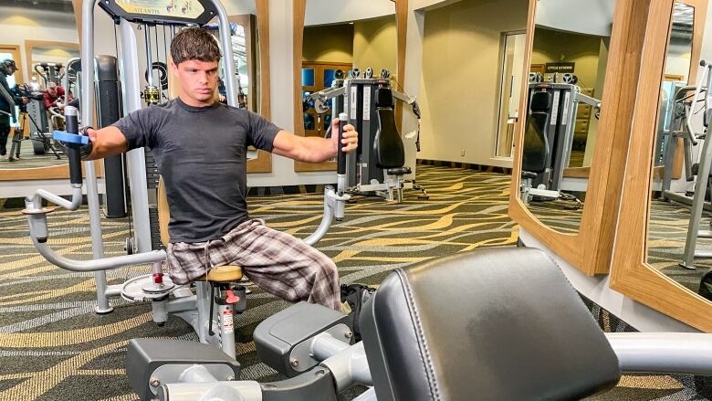 A young man with one leg lifts weights in a gym.