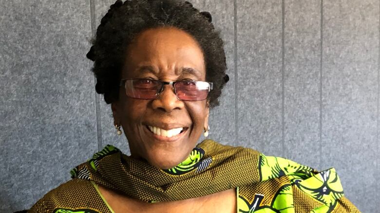 A smiling older woman in a green dress.