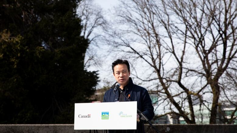 Vancouver Mayor Ken Sim is pictured at a podium.