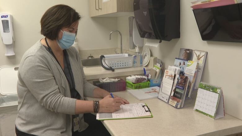 Dr. Krista Cassell fills out paperwork in an examination room.