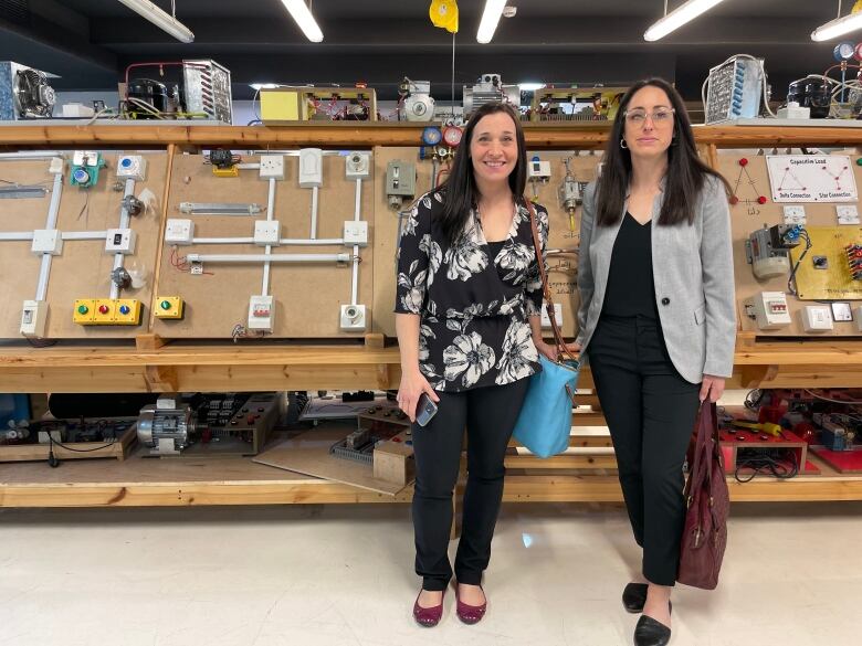 Two women are shown standing side by side with electrical switches behind them in a technical college classroom.