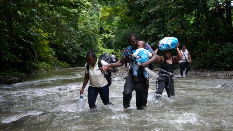 Haitian migrants wade through a river as they cross the Darien Gap, from Colombia into Panama, hoping to reach the U.S. on Oct. 15, 2022.