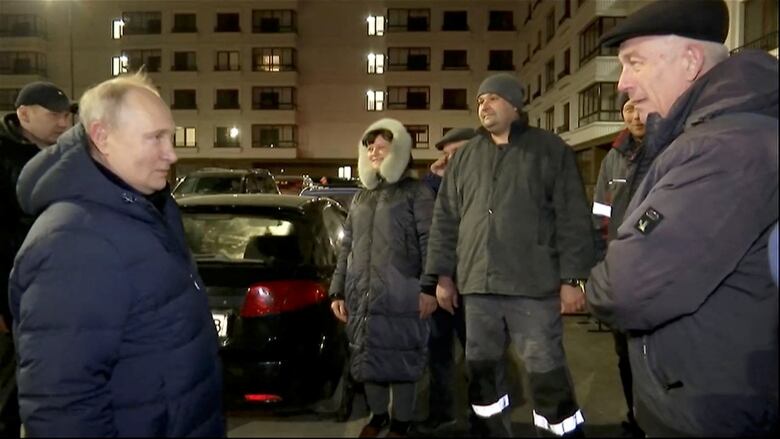 People stand outside an apartment complex.