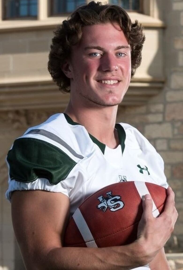 Matthew Baraniuk in his U of S Huskies football jersey holding a football.