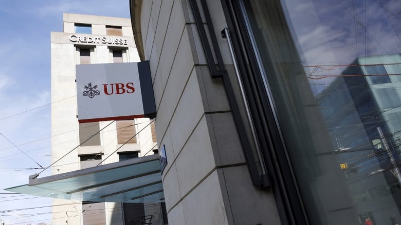 The logos of UBS and Credit Suisse are seen on the facades of neighbouring buildings. 