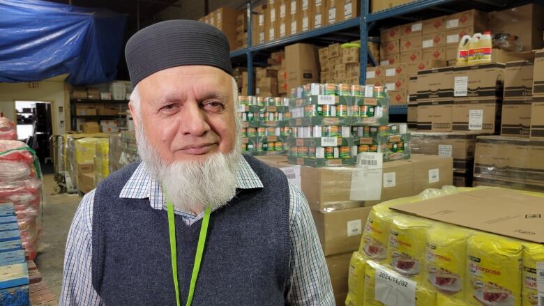 A bearded man wearing a round taqiyah cap is pictured at a food bank.