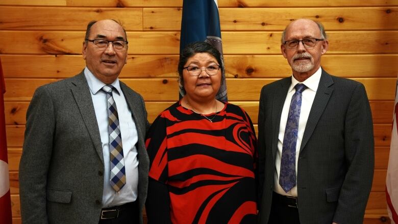 Three people, two men and one woman, stand looking at the camera. 