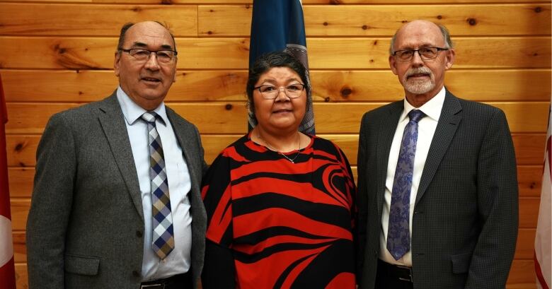 Three people, two men and one woman, stand looking at the camera. 