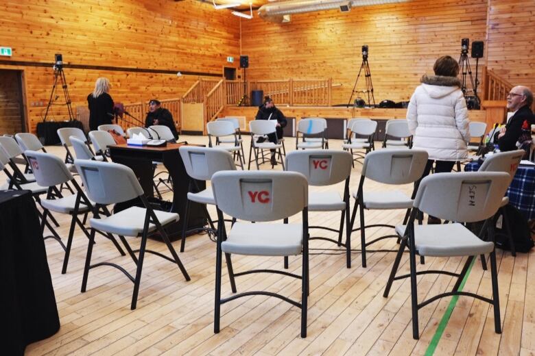 Chairs are arranged in a circle in a large room with wooden walls and ceiling. 