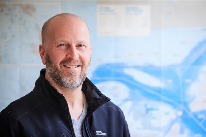 A man stands in front of a map of the Gulf of St. Lawrence