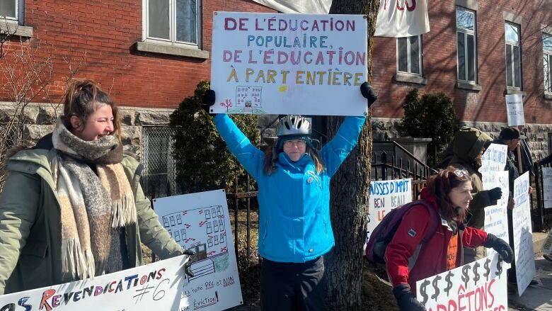 people holding signs in front of brick building