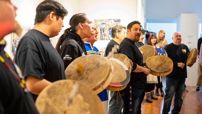 An Indigenous mens drum group sings.