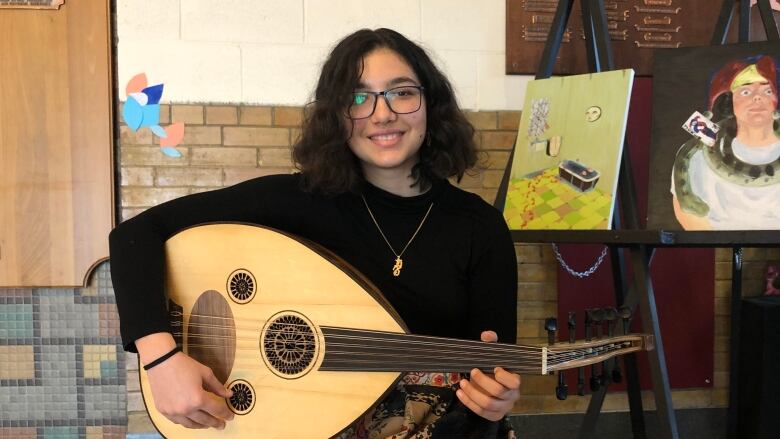 smiling girl with a guitar-like instrument on her lap