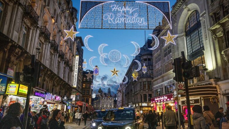 Cars pass under a string of lights in the shapes of crescent moons and stars on the eve of the first day of Ramadan.