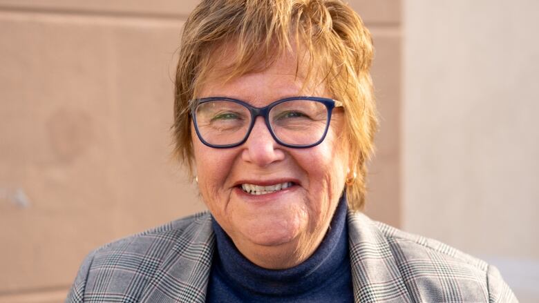 A woman with glasses and short hair, smiling.