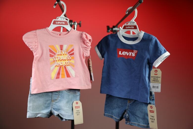 Left, a kid's outfit set with a pink shirt and light coloured jean shorts. Right, a similar kid's outfit set with a blue shirt and darker jean shorts. 