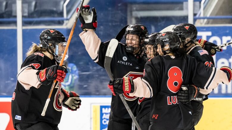 Hockey players hug and celebrate a goal.