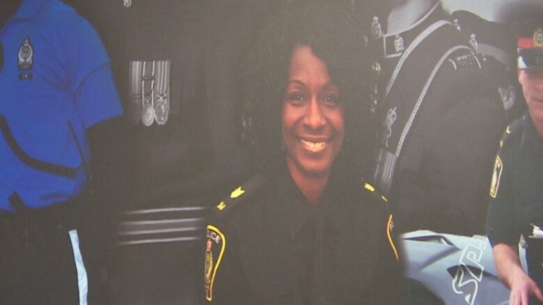 Photo of a Black female police officer with shoulder-length, curly hair pictured on a photo mural.