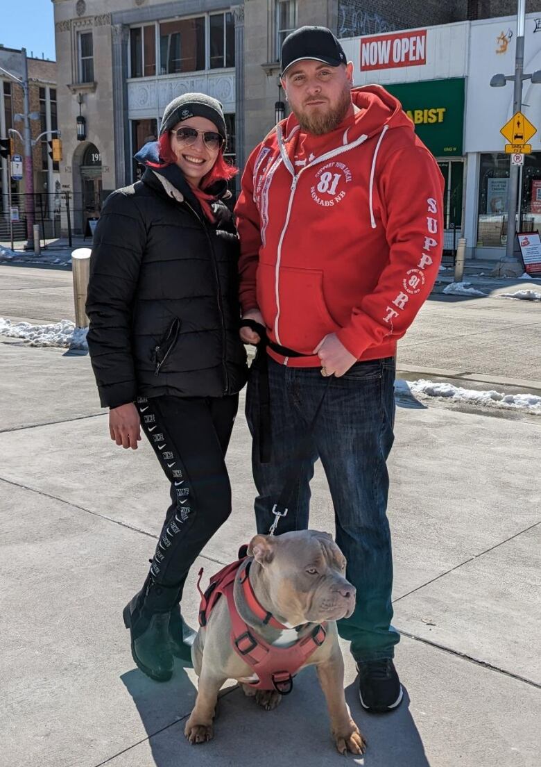 A woman and a man stand with their dog.