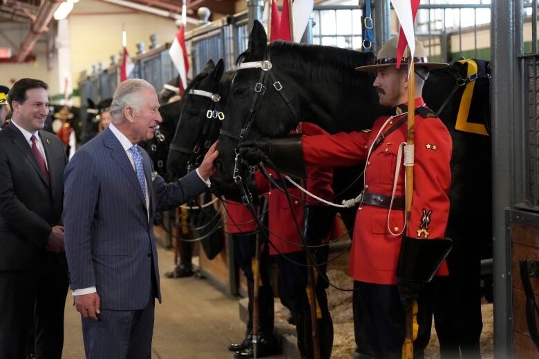 A person pats a horse while a police officer looks on.