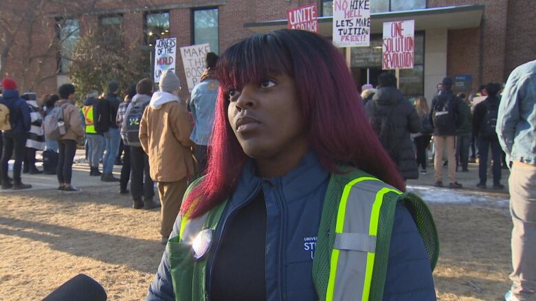 A woman stands outside the office for the University of Alberta board of governors.