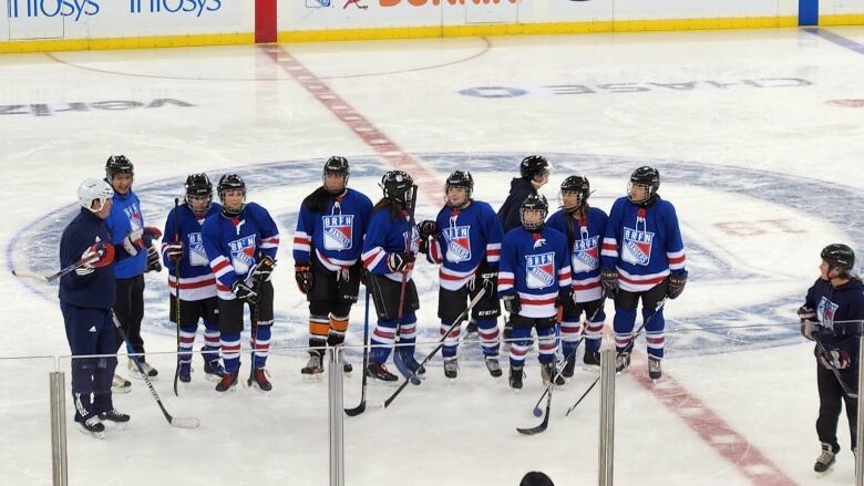 Group of female hockey players with professionals coaches on the New York Rangers home ice