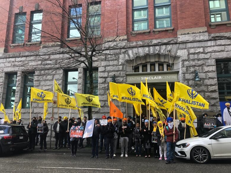 People at a rally in Vancouver on Saturday March 25 hold yellow flags advocating for a free state of Khalistan in India's Punjab region.