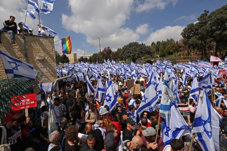 A crowd of people carrying Israeli flags is seen outside the country's parliament building.