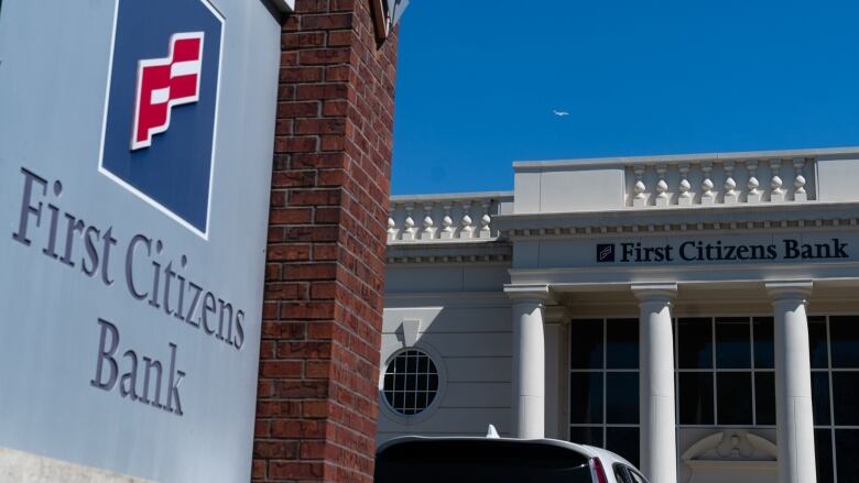 The First Citizens Bank logo is shown on a sunny day outside one of the bank's branches.