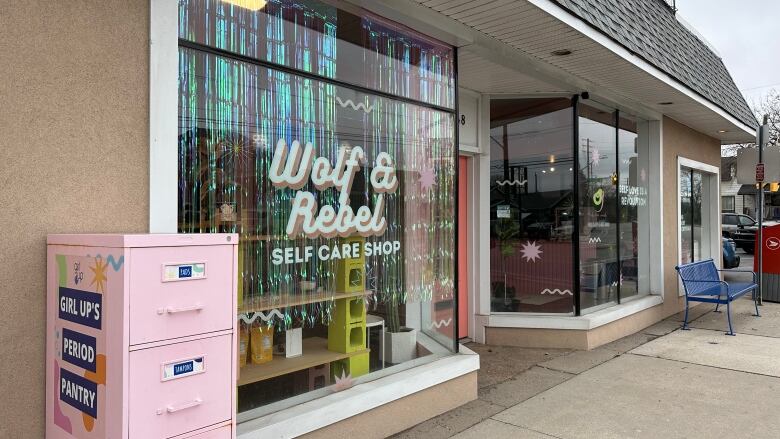 A storefront with a pink filing cabinet outside