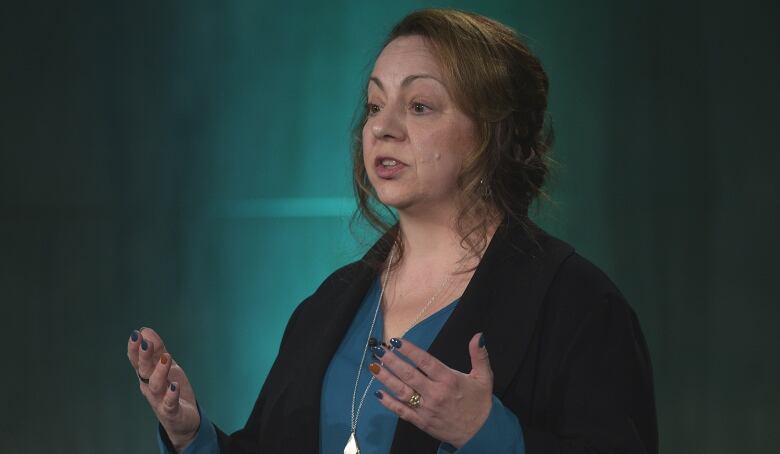 A woman stands indoors at a podium