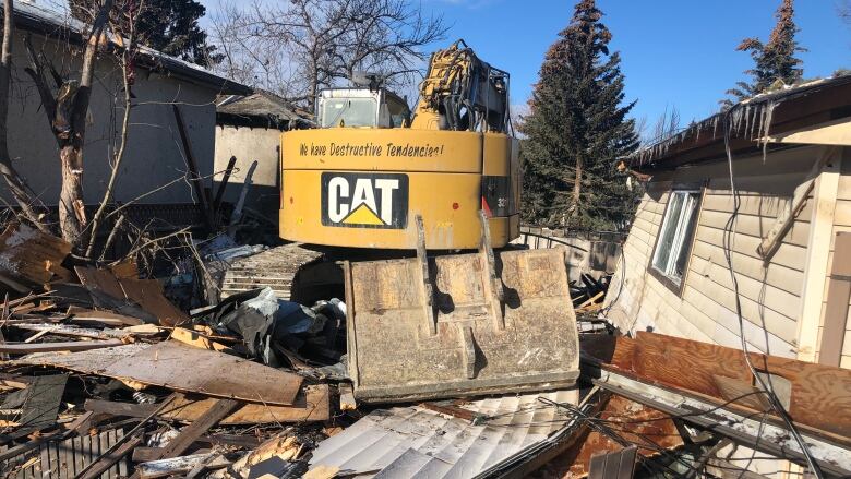 A yellow Cat backhoe sits on the wreckage of the home that exploded. 