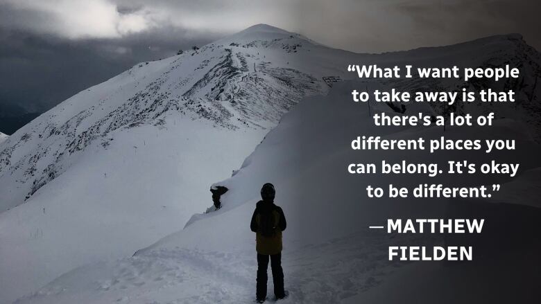 A boy stands in the snow on top of a mountain. 