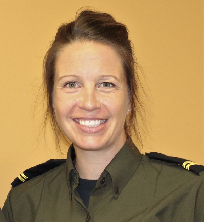 A smiling woman in an olive grey uniform with epaulets.