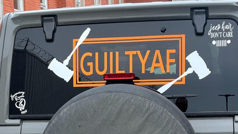 A grey jeep is parked outside of the Sudbury courthouse, with a decal in the back window reading 'Guilty AF' with two pictures of gavels. 