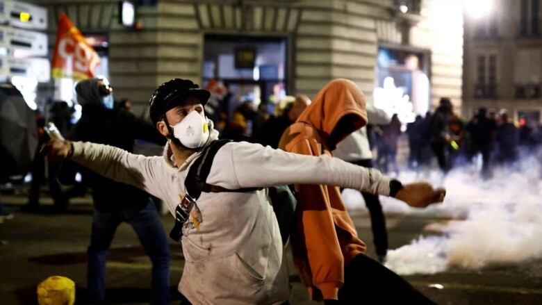 A demonstrator trows a projectile amid clashes during a protest after French Prime Minister Elisabeth Borne used a special clause in the French constitution to push a pensions reform bill through the National Assembly without a vote, in Nantes, France, Thursday. (Stephane Mahe/Reuters)