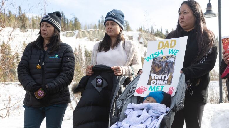 Women in tuques with poster, baby.