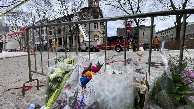 Flowers on a fence with a burned building behind.