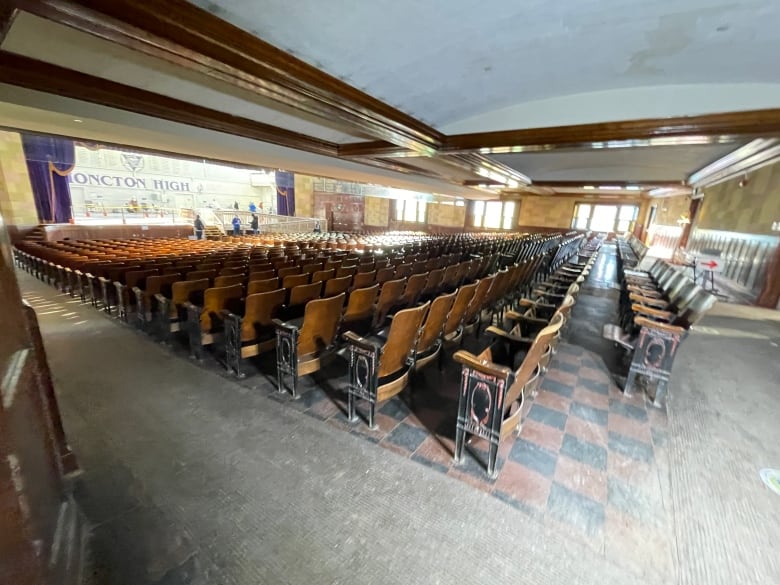 Rows of wooden seats and a stage with the words 