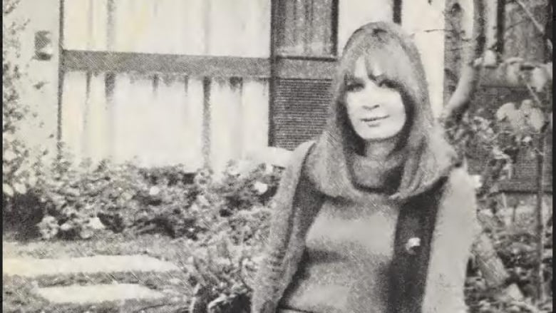 A woman sits on a garden stone fence in a black and white photograph. 