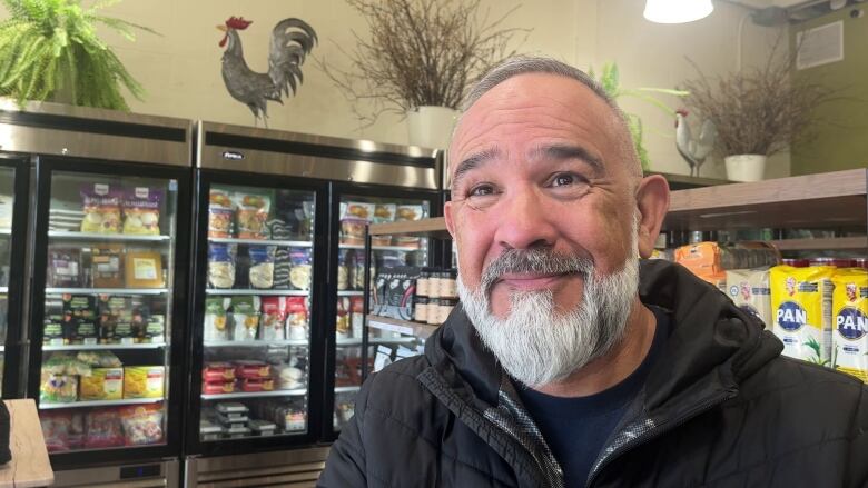 A man stands in front of a grocery store.