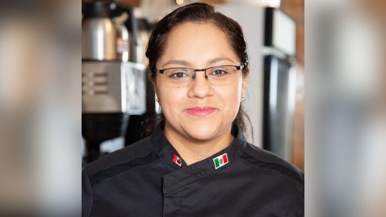 A woman wears a black shirt and looks at the camera.