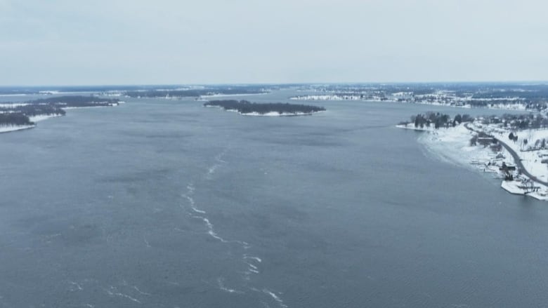 An aerial view of a wide river, running through a wintry landscape.