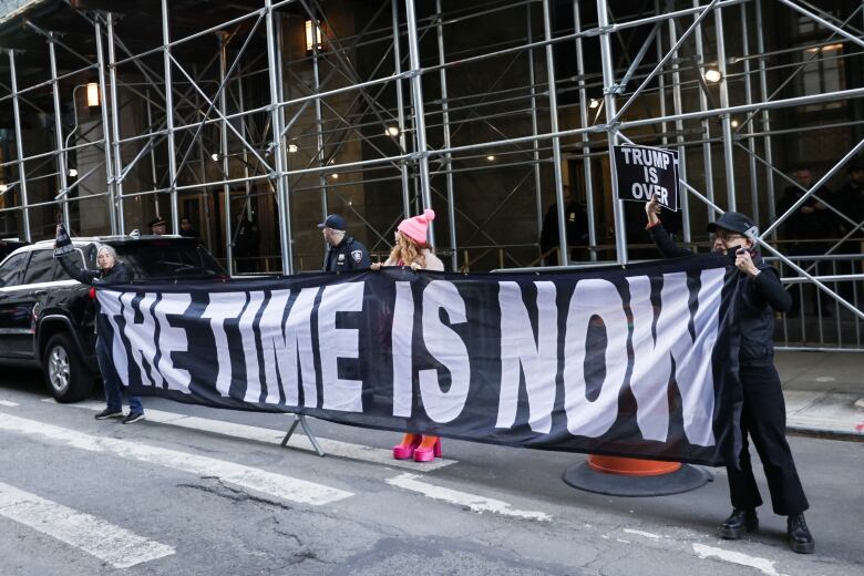 Demonstrators on the street hold a banner.