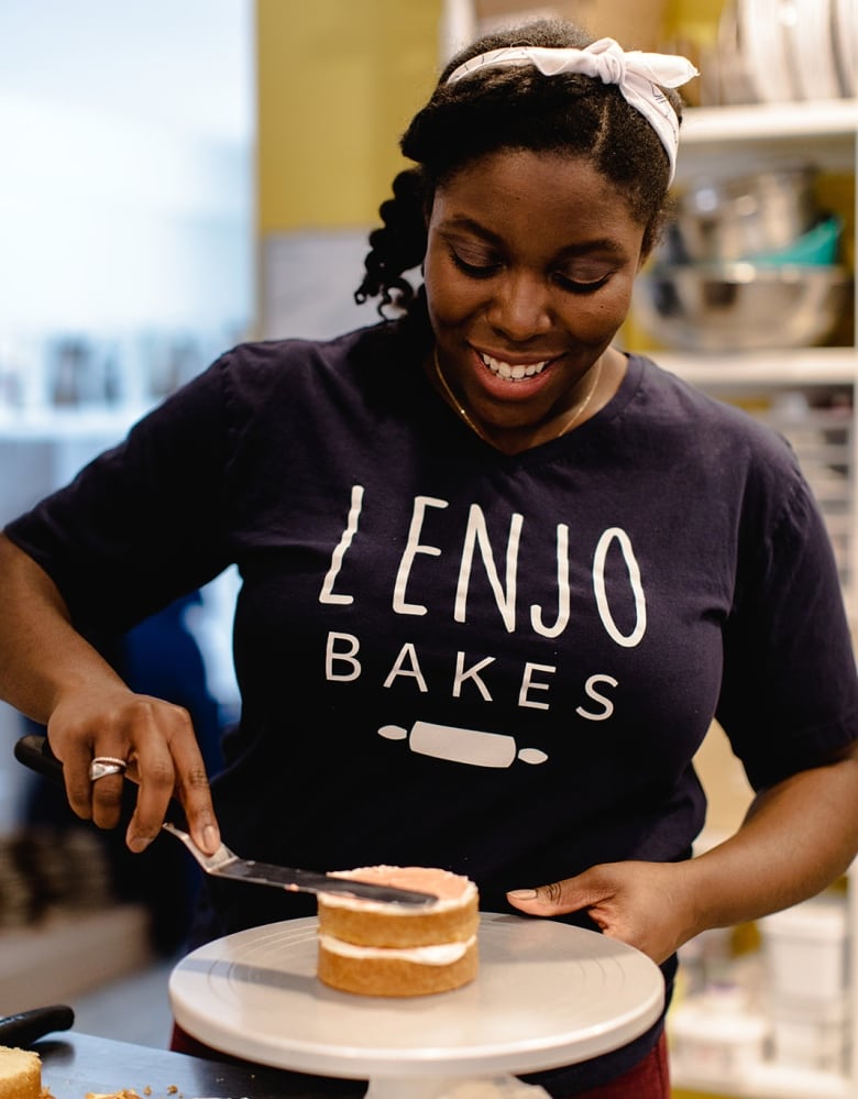 A baker ices the second layer of a cake.