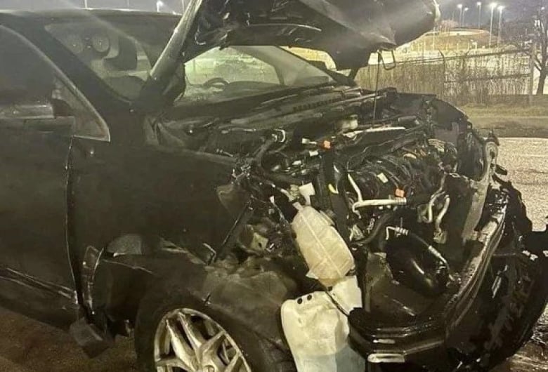 A damaged black SUV with the hood open after a crash.