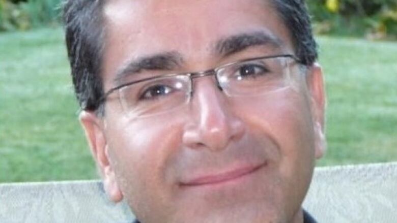 A close-up profile picture of a clean-shaven man with glasses and dark hair.