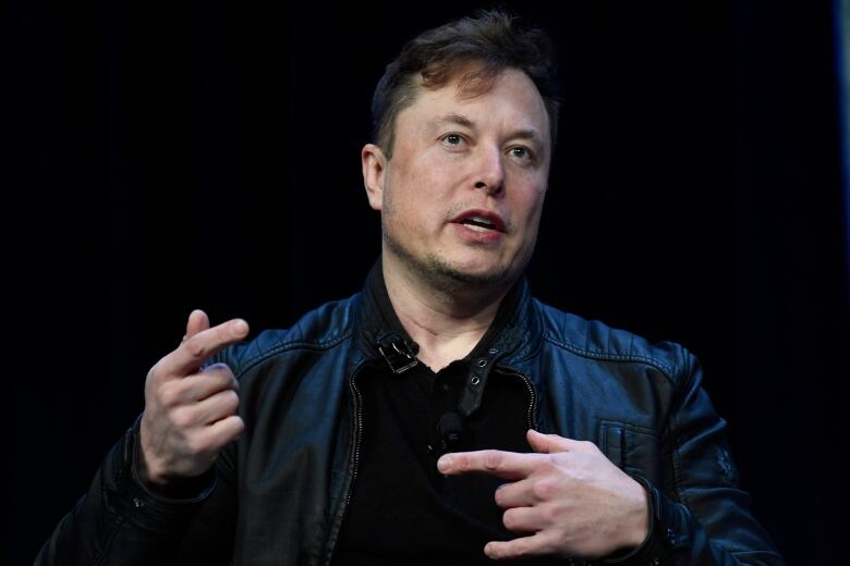 A man in black shirt and jacket speaks.