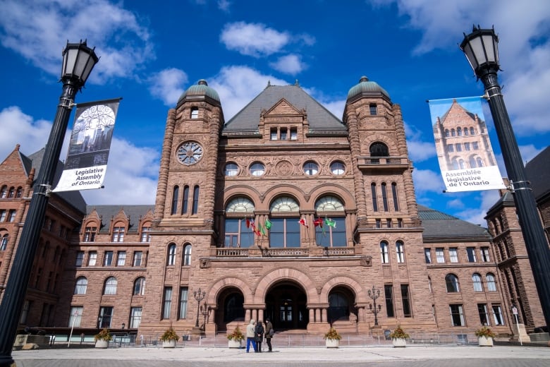 The front of the Ontario Legislature historic building is pictured in downtown Toronto against a blue sky.