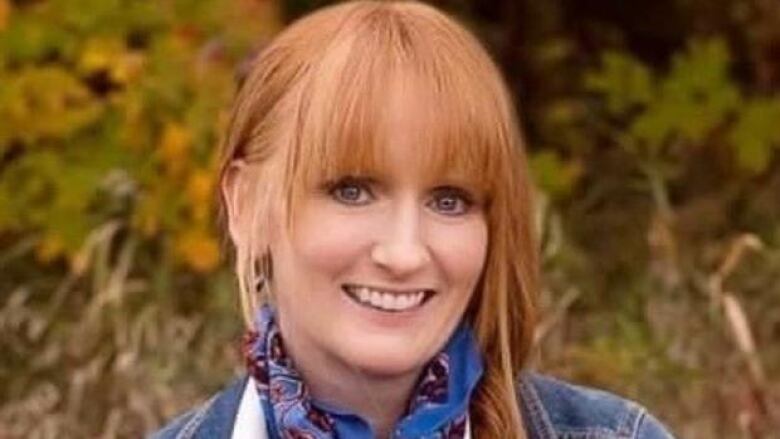 Portrait of a smiling redheaded woman wearing a jean jacket and a neck scarf